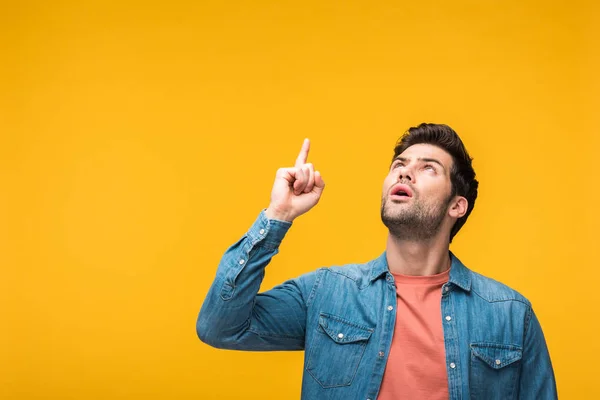Confused handsome man pointing with finger isolated on yellow — Stock Photo