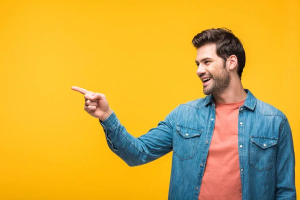 Smiling handsome man pointing with finger isolated on yellow — Stock Photo