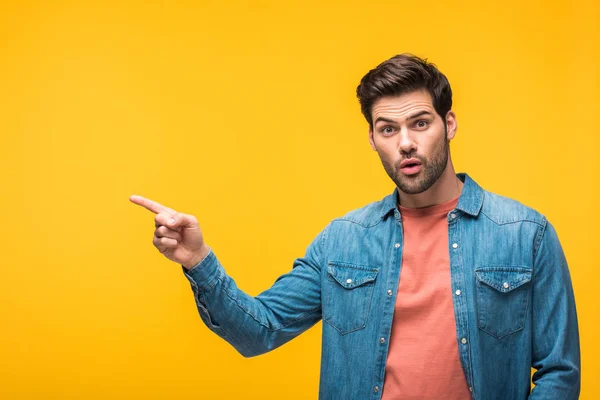 Surprised handsome man pointing with finger isolated on yellow — Stock Photo