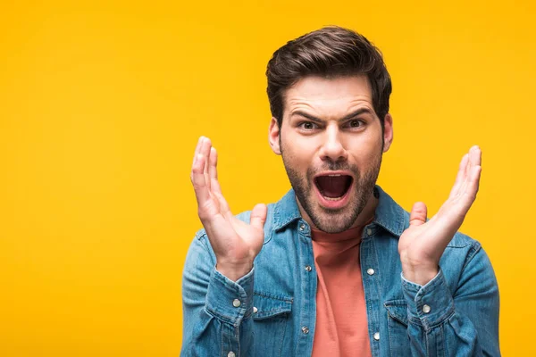 Surprised handsome man gesturing with hands isolated on yellow — Stock Photo