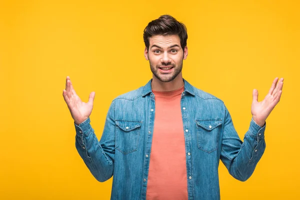 Confused handsome man gesturing with hands and looking at camera isolated on yellow — Stock Photo