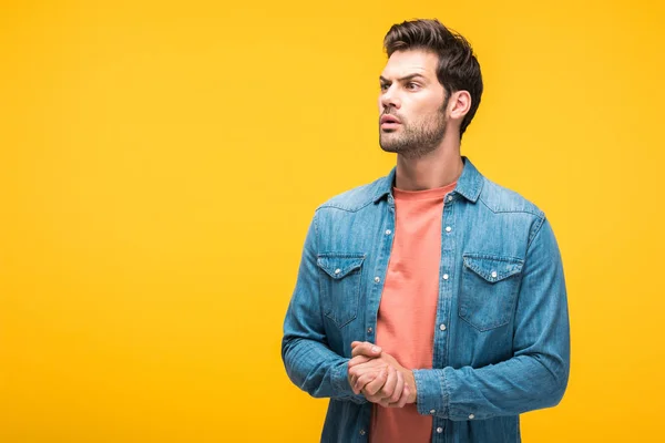 Confused handsome man with clenched hands isolated on yellow with copy space — Stock Photo