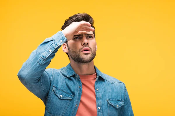 Hombre guapo confundido con la mano en la frente aislado en amarillo - foto de stock