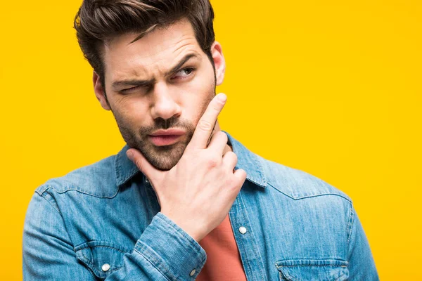 Confused handsome man touching chin isolated on yellow — Stock Photo