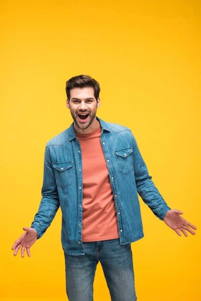 Aufgeregter schöner Mann mit offenen Handflächen, isoliert auf gelb — Stockfoto