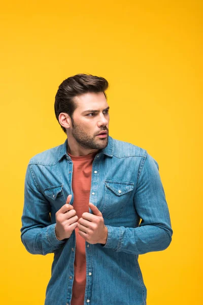 Hombre guapo asustado mirando hacia otro lado aislado en amarillo - foto de stock