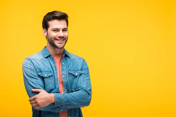 Smiling handsome man with crossed arms isolated on yellow with copy space — Stock Photo