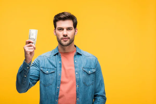 Schöner Mann hält Geld isoliert auf gelb mit Kopierraum — Stockfoto