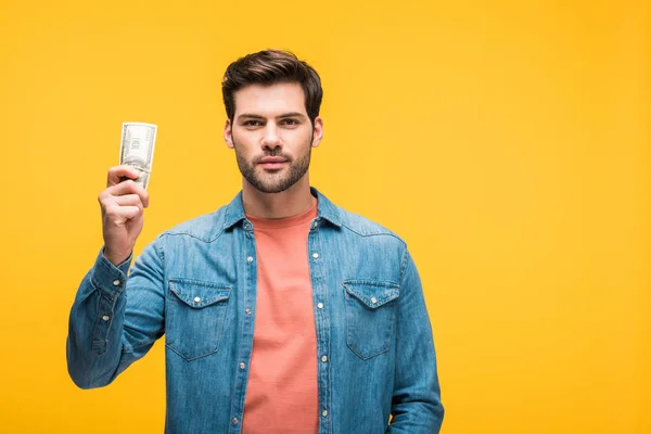 Bonito homem segurando dinheiro isolado no amarelo com espaço de cópia — Fotografia de Stock