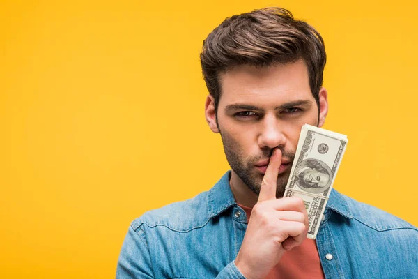 Schöner Mann macht Schweigegeste und hält Dollarnoten isoliert auf gelb — Stockfoto