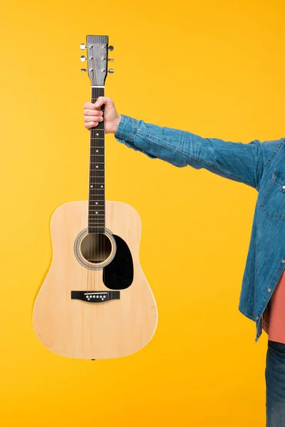 Vista recortada del hombre sosteniendo la guitarra acústica aislado en amarillo - foto de stock