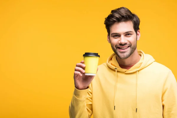 Schöner Mann in Kapuzenpulli mit Kaffee zum Ausziehen auf gelb — Stockfoto