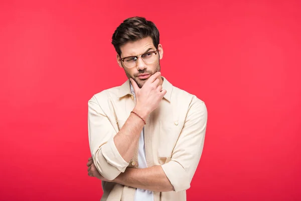 Pensive man in glasses touching chin isolated on pink — Stock Photo