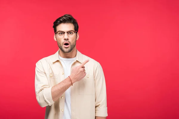 Überrascht schöner Mann zeigt mit dem Finger auf rosa mit Kopierraum — Stockfoto