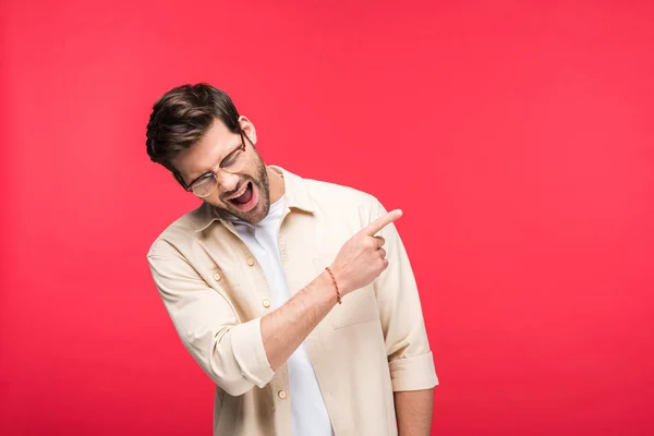 Feliz hombre guapo señalando con el dedo en el espacio de copia aislado en rosa — Stock Photo