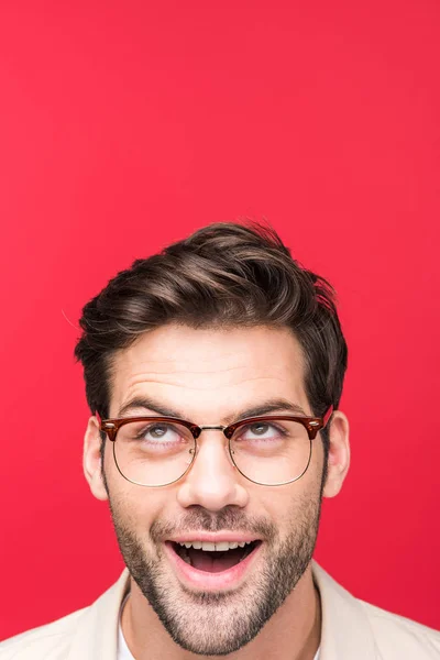 Sorprendido hombre guapo en gafas mirando arriba aislado en rosa - foto de stock