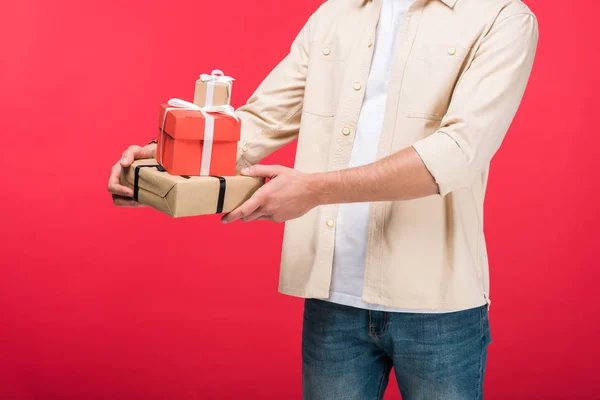 Vista recortada del hombre sosteniendo regalos en rosa - foto de stock