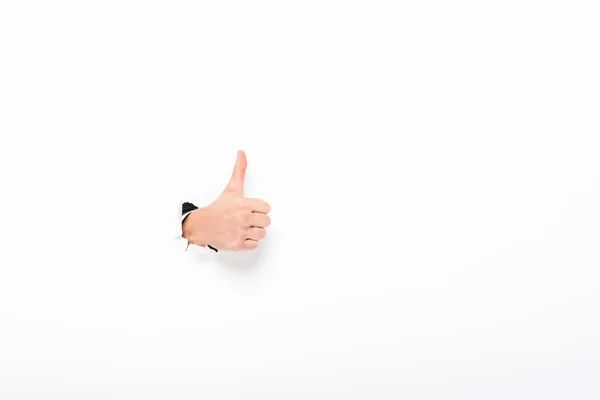 Man showing thumb up from hole in paper wall on white with copy space — Stock Photo