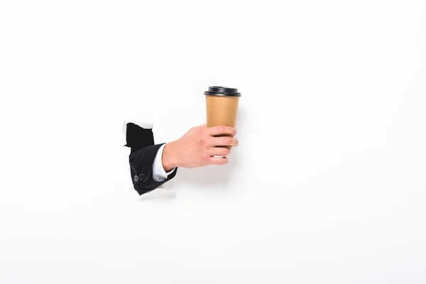Vue recadrée de l'homme tenant du café pour aller du trou dans le mur sur blanc avec espace de copie — Stock Photo