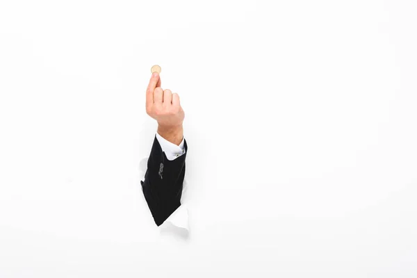 Cropped view of man holding coin through hole in paper wall on white — Stock Photo