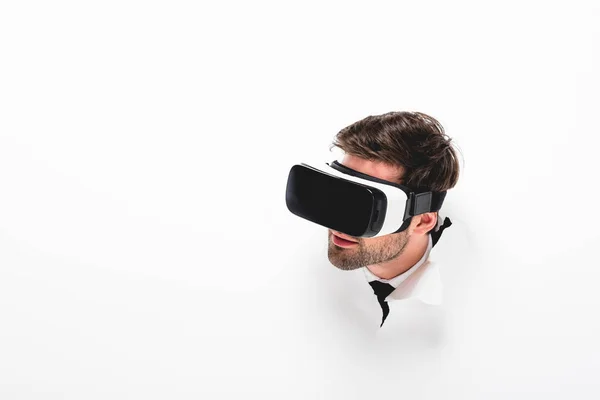 Bearded man in Virtual reality headset behind hole in wall on white with copy space — Stock Photo