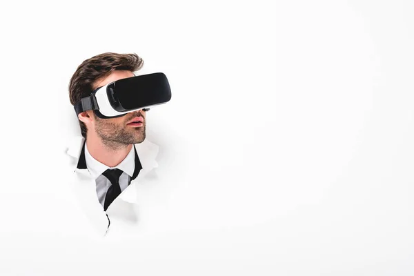 Man in Virtual reality headset behind hole in wall on white with copy space — Stock Photo