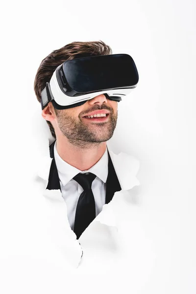 Усміхнений чоловік у гарнітурі віртуальної реальності за дірою в стіні на білому — стокове фото