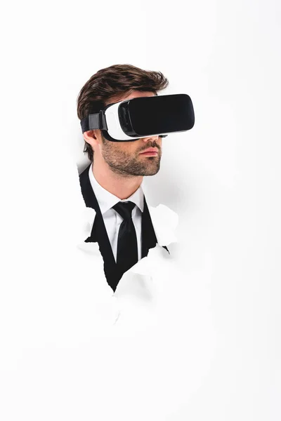 Man in suit and Virtual reality headset behind hole in wall on white — Stock Photo