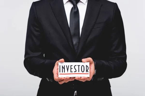 Abgeschnittene Ansicht des Geschäftsmannes im Anzug, der Karte mit Anlegerwort auf grau isoliert — Stockfoto