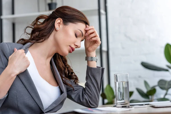 Красивая деловая женщина с закрытыми глазами страдает от жары в офисе — стоковое фото
