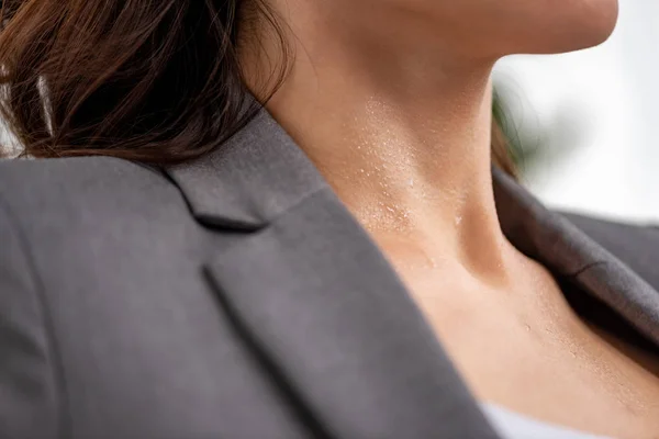 Ausgeschnittene Ansicht einer jungen Frau, die unter Hitze leidet, mit Schweiß am Hals auf Weiß — Stockfoto