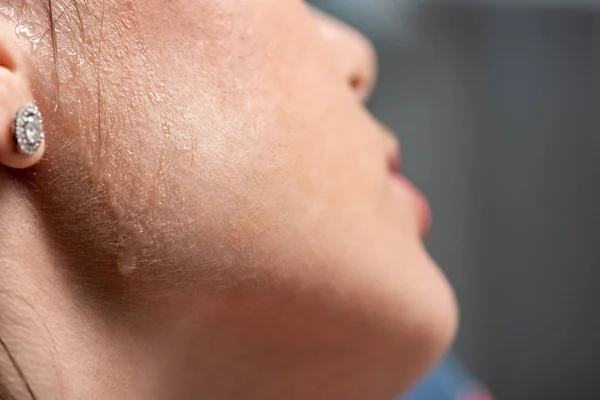 Vista recortada de la mujer joven con sudor en la cara que sufre de calor en gris - foto de stock