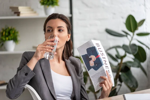 Bela mulher de negócios água potável de vidro e acenando jornal de negócios enquanto sofre de calor no escritório — Fotografia de Stock