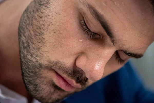 Schöner erschöpfter Mann mit verschwitztem Gesicht, der unter Hitze auf grau leidet — Stockfoto