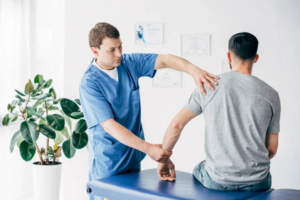 Physiotherapist massaging arm of patient on massage table in hospital — Stock Photo