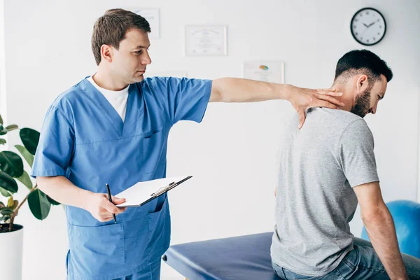 Chiropractor with diagnosis and pen massaging neck of man in hospital — Stock Photo