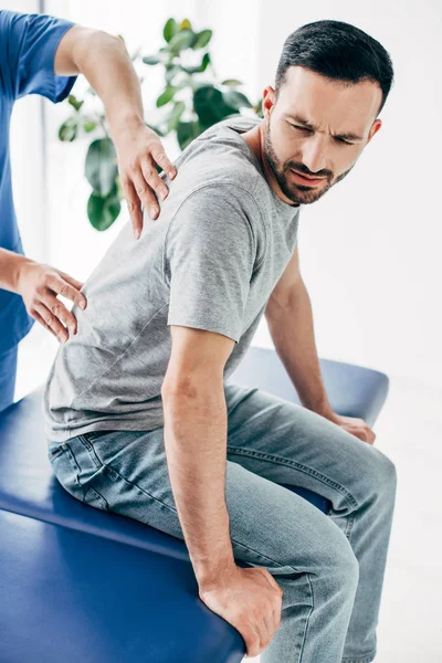 Chiropraktiker massiert Rücken eines gut aussehenden Mannes im Krankenhaus — Stockfoto