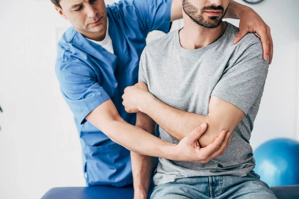 Physiotherapeut massiert Arm einer Patientin im Krankenhaus — Stockfoto