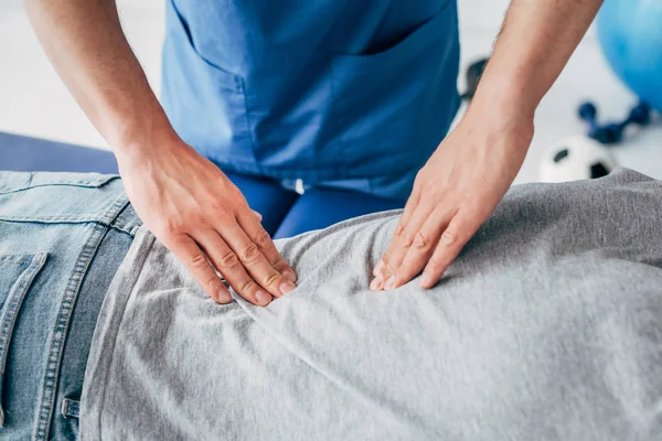 Cropped view of chiropractor massaging back of man in hospital — Stock Photo