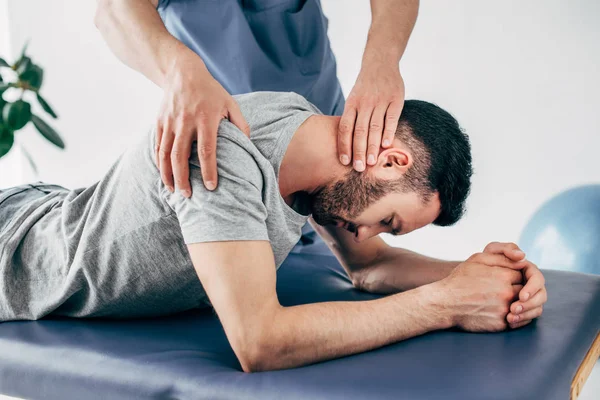 Quiroprático massageando ombro e pescoço do homem na mesa de massagem no hospital — Fotografia de Stock