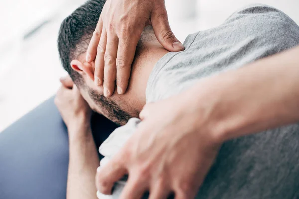 Selective focus of chiropractor massaging neck of man in hospital — Stock Photo