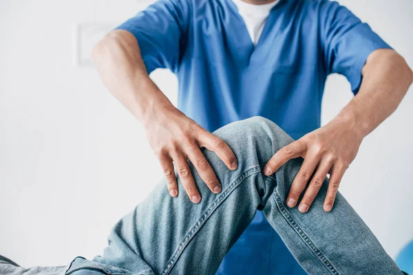 Vew parcial do fisioterapeuta massageando a perna do paciente no hospital — Fotografia de Stock