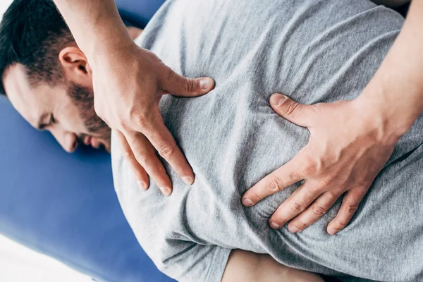 Physiotherapist massaging back of man lying on Massage Table in hospital — Stock Photo