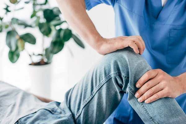 Vista recortada do fisioterapeuta massageando a perna do paciente no hospital — Fotografia de Stock