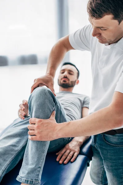 Selective focus of Physiotherapist massaging leg of patient in hospital — Stock Photo