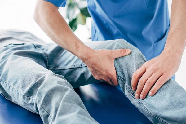 Cropped view of chiropractor massaging leg of patient in hospital — Stock Photo