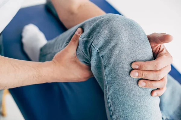 Vista ravvicinata del fisioterapista che massaggia la gamba del paziente in ospedale — Foto stock