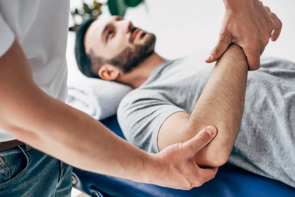 Selektiver Fokus des Chiropraktikers massiert Arm des Patienten im Krankenhaus — Stockfoto