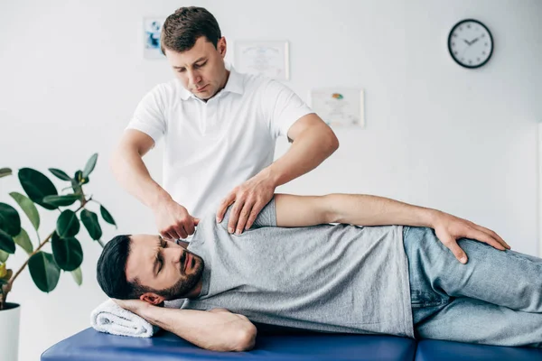 Chiropractor massaging arm of patient on massage table in hospital — Stock Photo