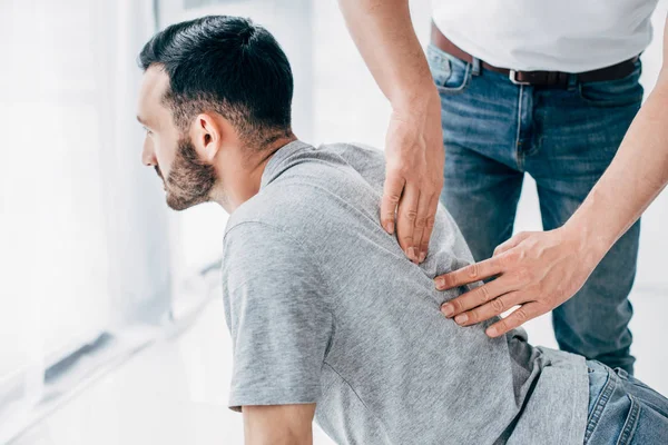 Chiropractor massaging back of bearded man in hospital — Stock Photo